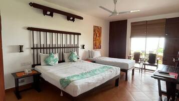A hotel room with two beds, a ceiling fan, a painting, and a window with blinds.