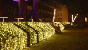 Un bâtiment agrémenté de haies illuminées, d’une colonne en briques et d’espaces aménagés pour s’asseoir à l’extérieur.