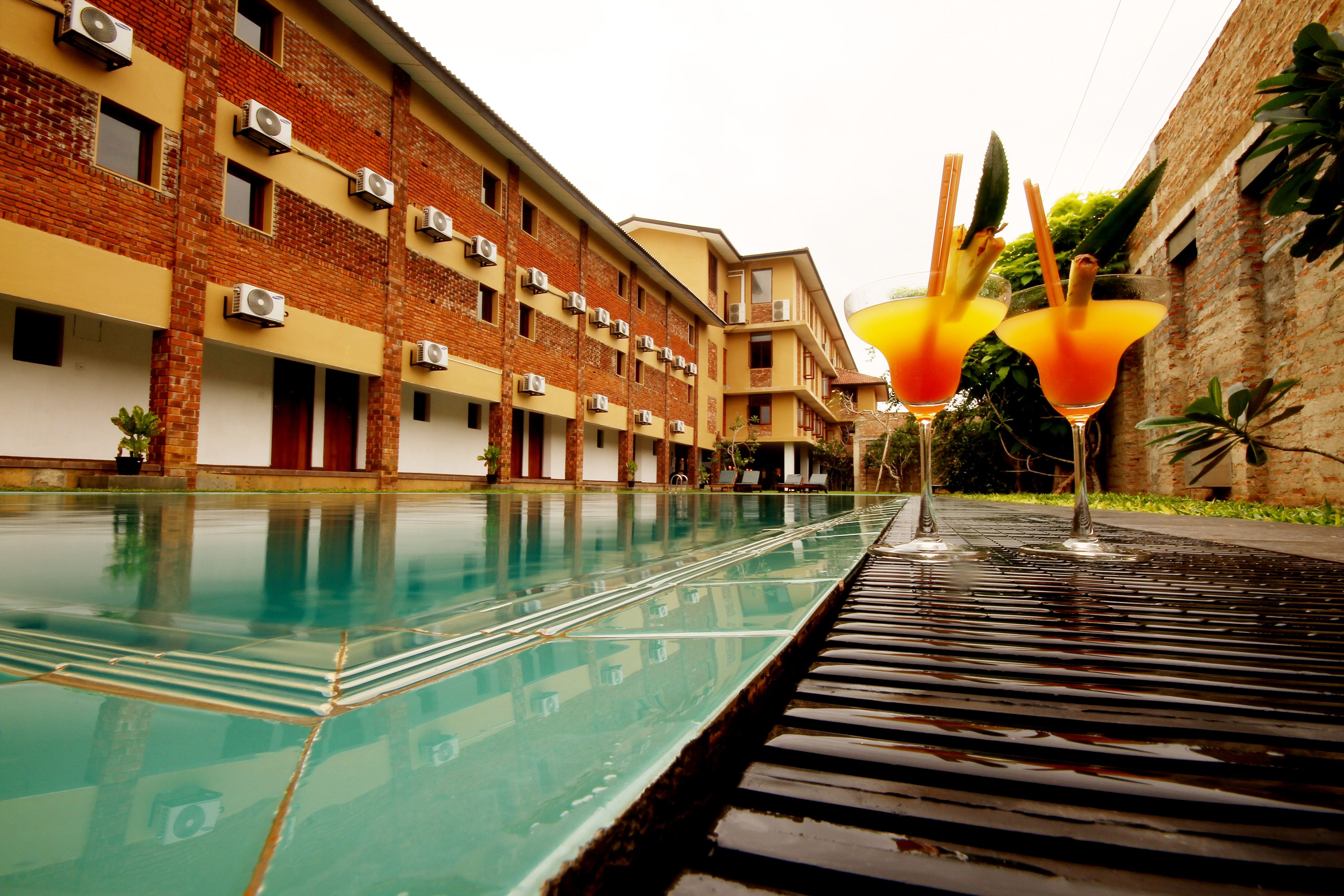 A swimming pool with a clear water surface, surrounded by a brick building with multiple air conditioning units.