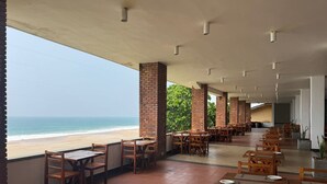 Un restaurant situé en bord de mer, avec une terrasse, des piliers en briques et une vue sur l’océan.