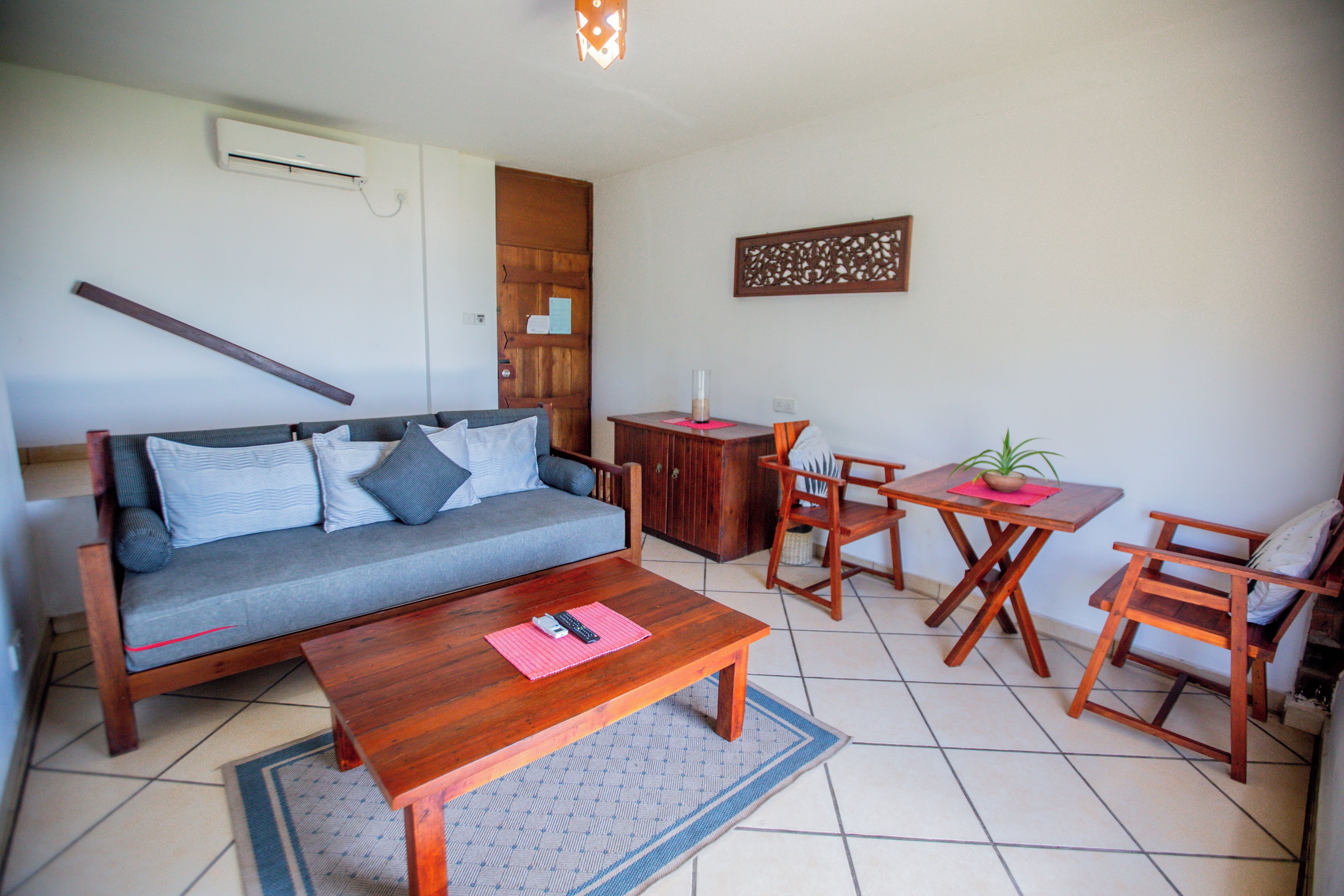 A living room with a sofa, a coffee table, a wooden dining table, and a chair.