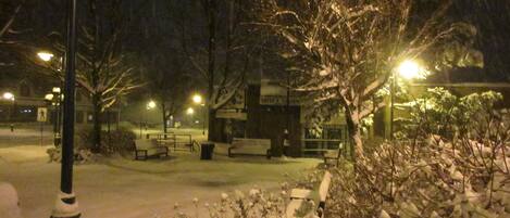 A snow-covered outdoor area with benches and a building in the background.