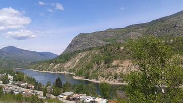 A lakeside village with houses along the shore, surrounded by mountains and greenery.