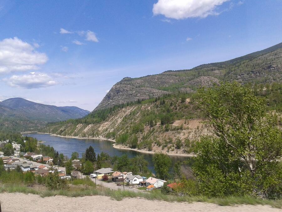 A lakeside village with houses along the shore, surrounded by mountains and greenery.