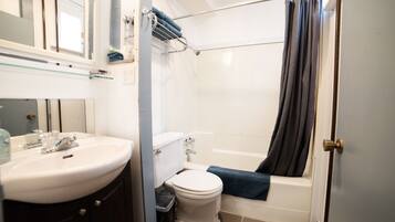 A bathroom with a sink, toilet, bathtub, and a shower curtain.