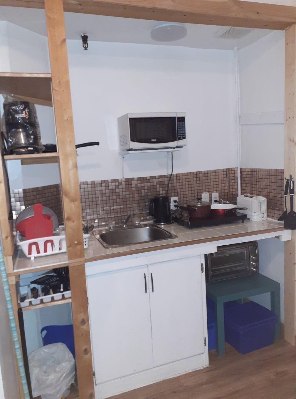 A compact kitchen with a microwave, sink, and basic appliances.