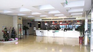 Un vestíbulo espacioso con mostrador de recepción, decoraciones navideñas y un diseño de techo moderno.