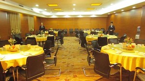 Un salón de conferencias con varias mesas y sillas, dispuestas en forma de U.