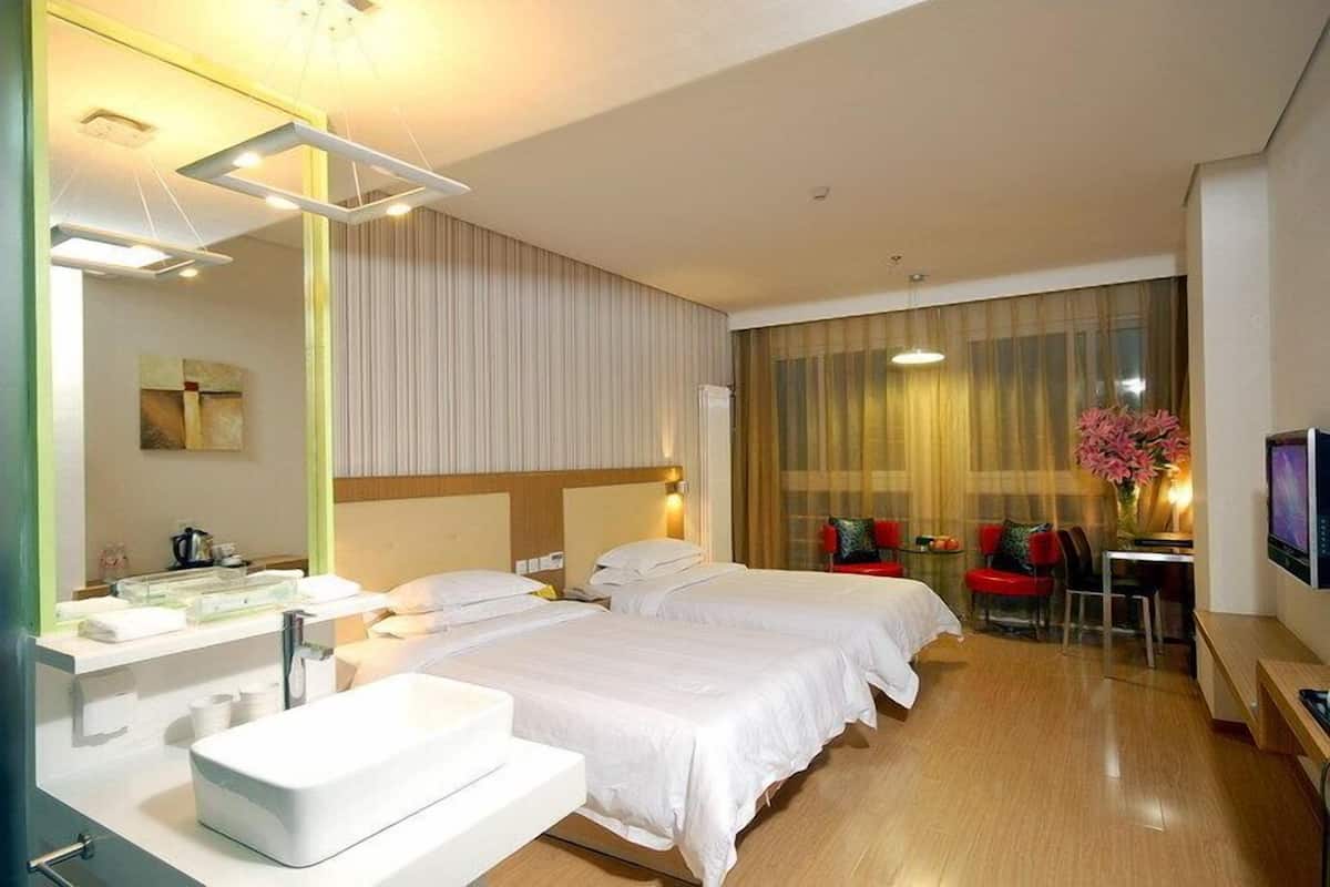 A hotel room with two beds, a large mirror, a sink, a TV, and a desk with a chair.
