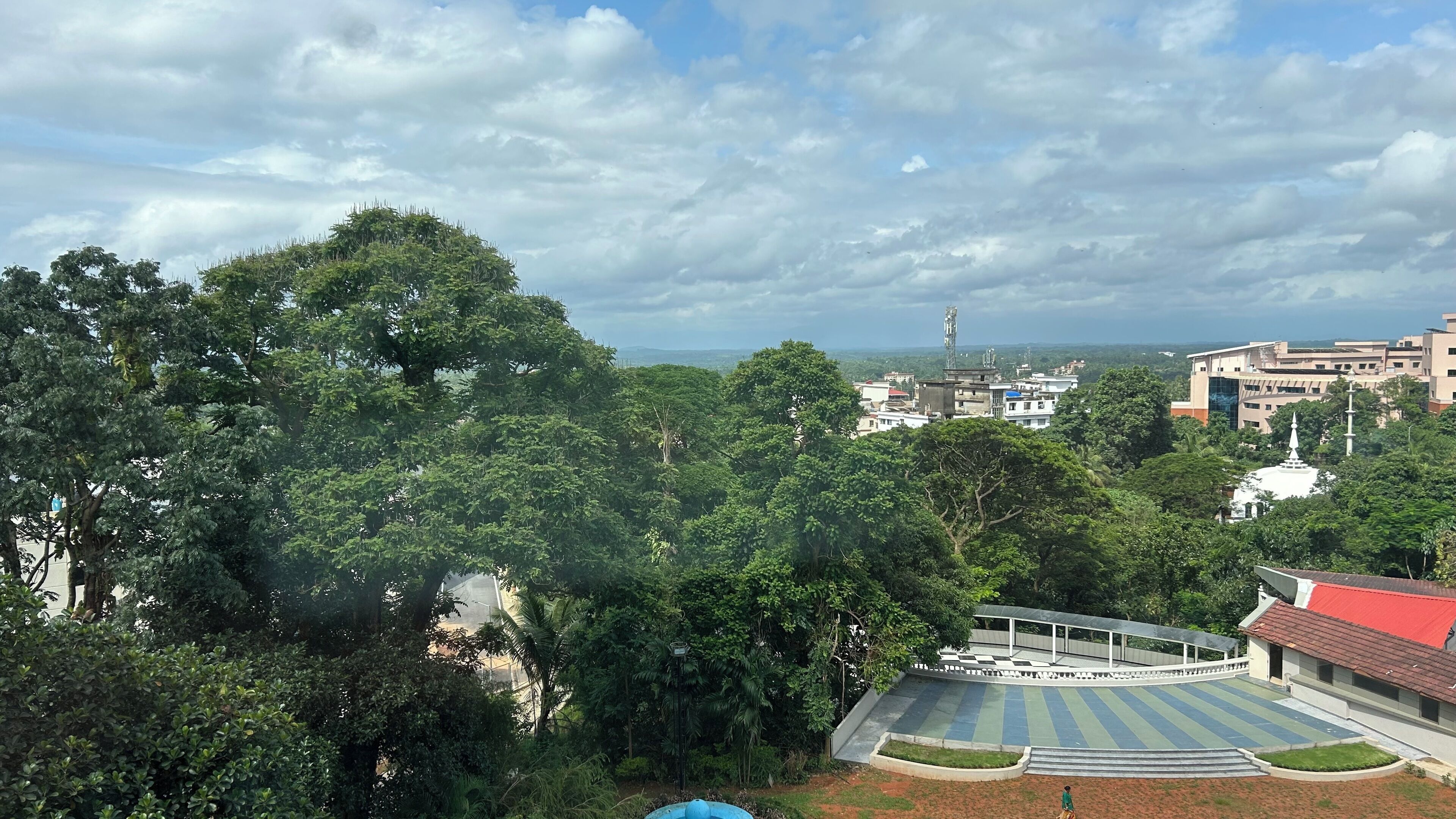 Un parque con un área de juegos, rodeado de árboles y edificios.