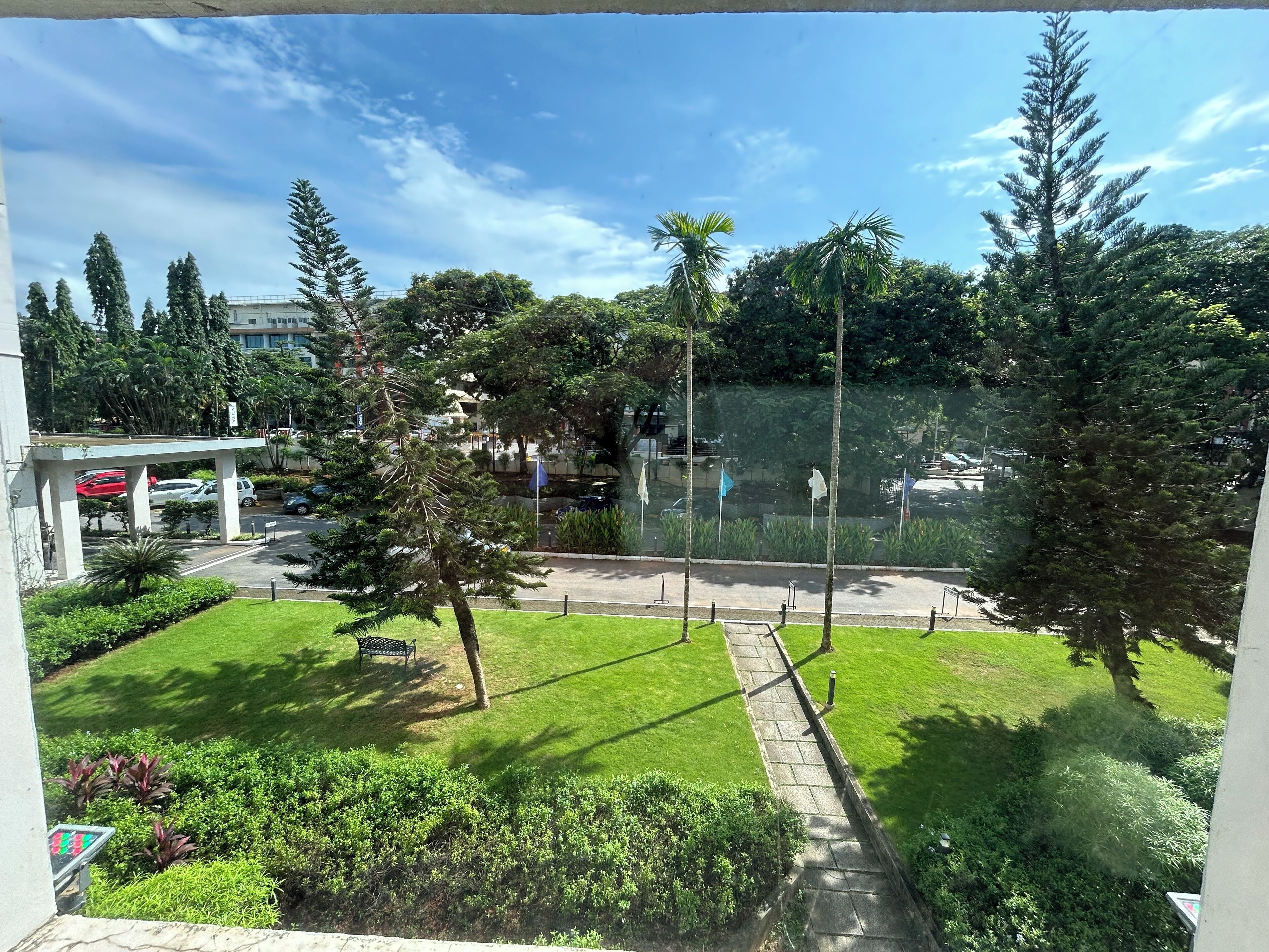 A view of a courtyard with a grassy area, trees, and a parking lot.