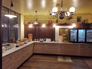 A kitchen with wooden cabinets, a refrigerator, and a chandelier. - Hotel Le Sully (La Roche-sur-Yon)