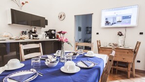 Un coin repas avec une nappe bleue, des assiettes blanches et un vase rempli de fleurs.