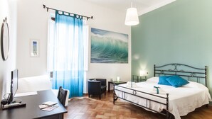 Une chambre à coucher comprenant un lit, un bureau avec un ordinateur, une chaise, une table de chevet et une lampe fixée au mur.