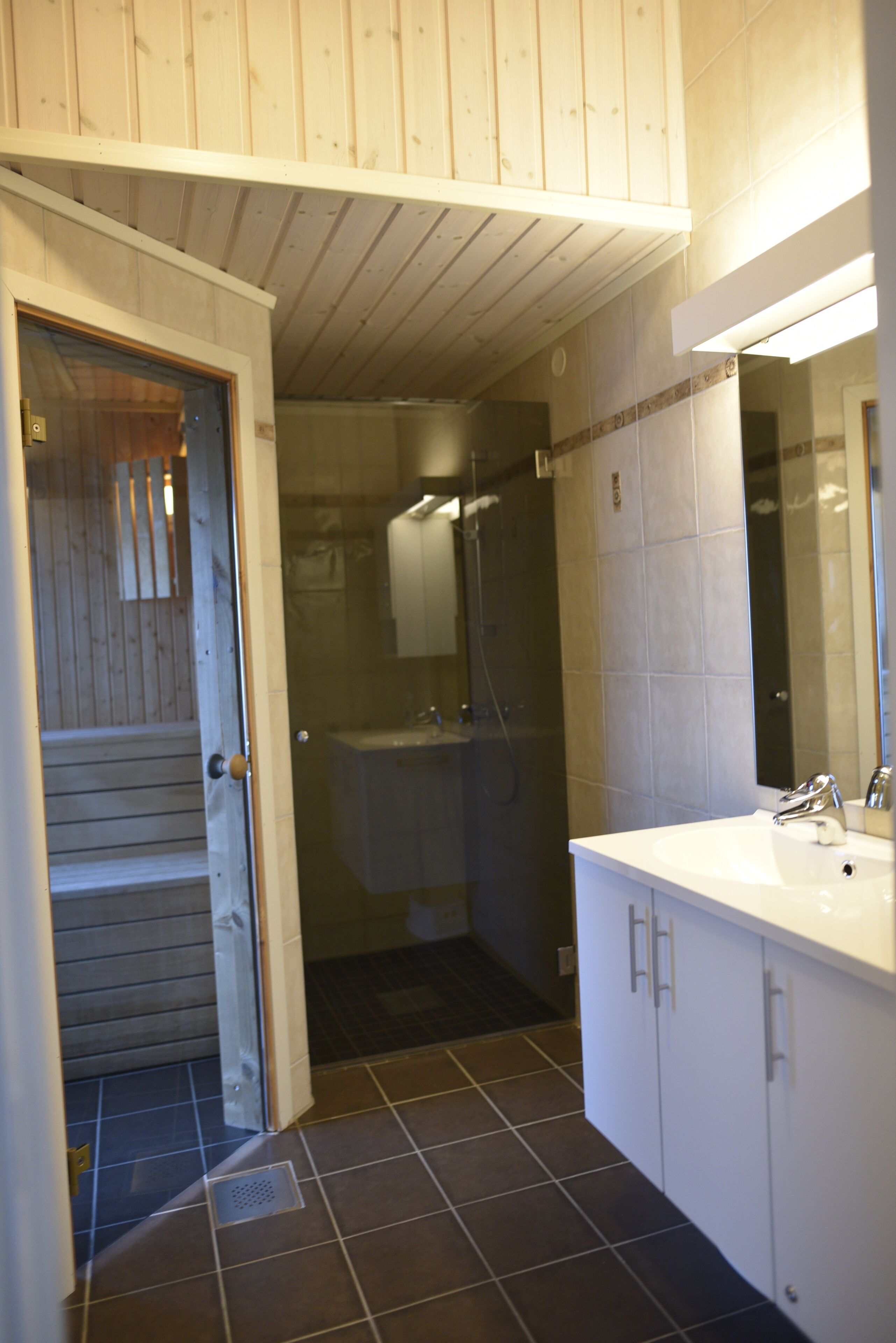 A bathroom with a shower, sink, and cabinets.