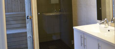 A bathroom with a shower, sink, and cabinets.