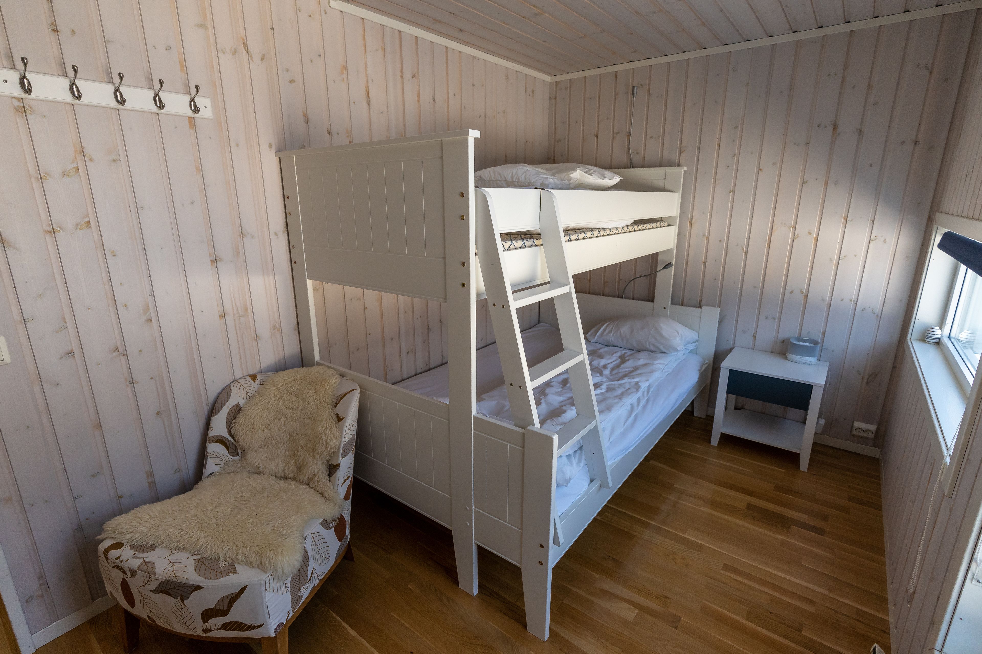 A bunk bed room with a chair and a nightstand.