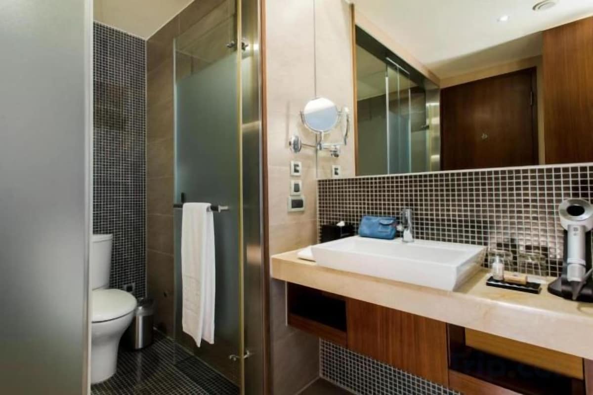 A modern bathroom with a glass shower enclosure, a white toilet, a sink with a mirror, and a towel rack.