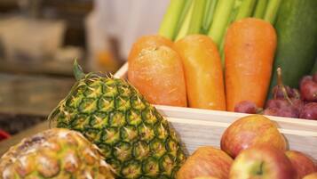 A wooden fruit and vegetable display with apples, pineapple, celery, carrots, and grapes.