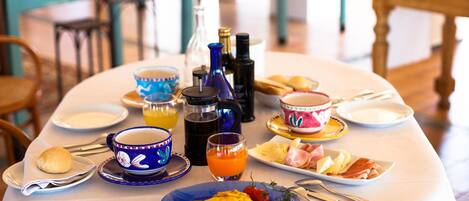 A dining table set with plates, bowls, a coffee pot, and a bottle of olive oil.
