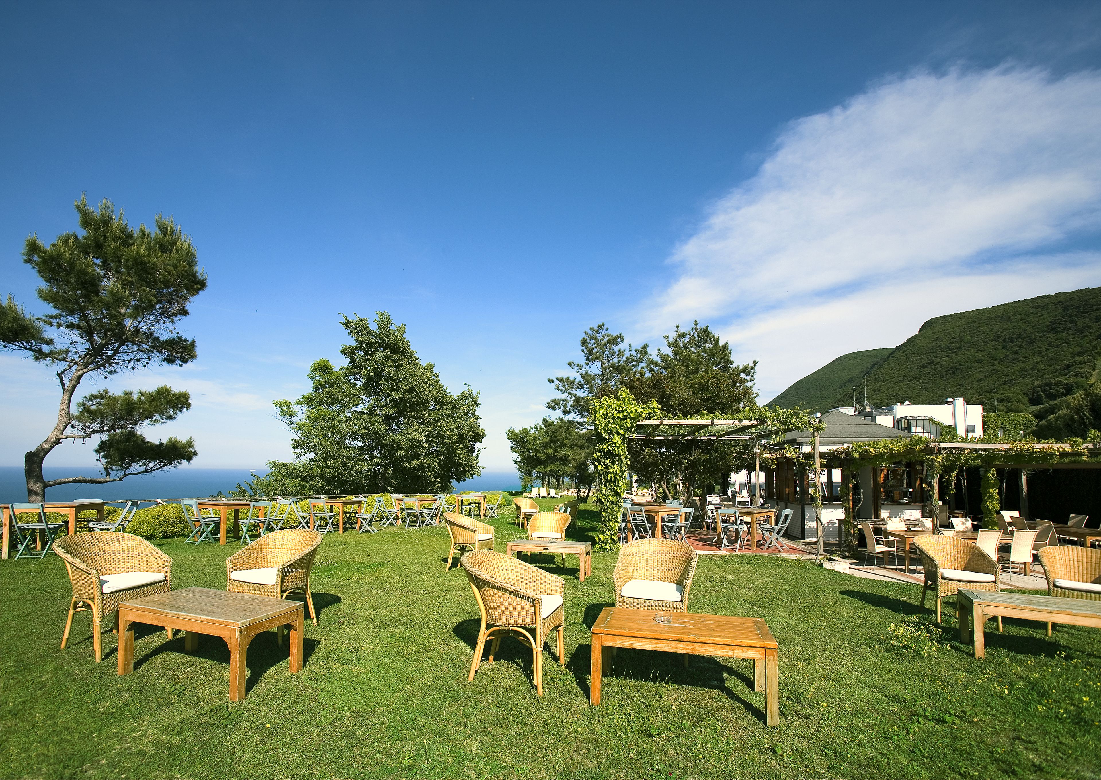 An outdoor seating area with wicker furniture and a view of the sea.