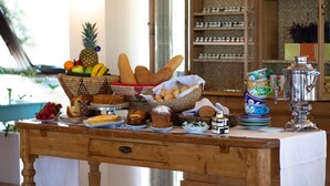 Un bufé de desayuno con pan, bollería, frutas y un samovar.