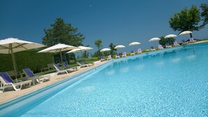 Una piscina con sillones de descanso y sombrillas.