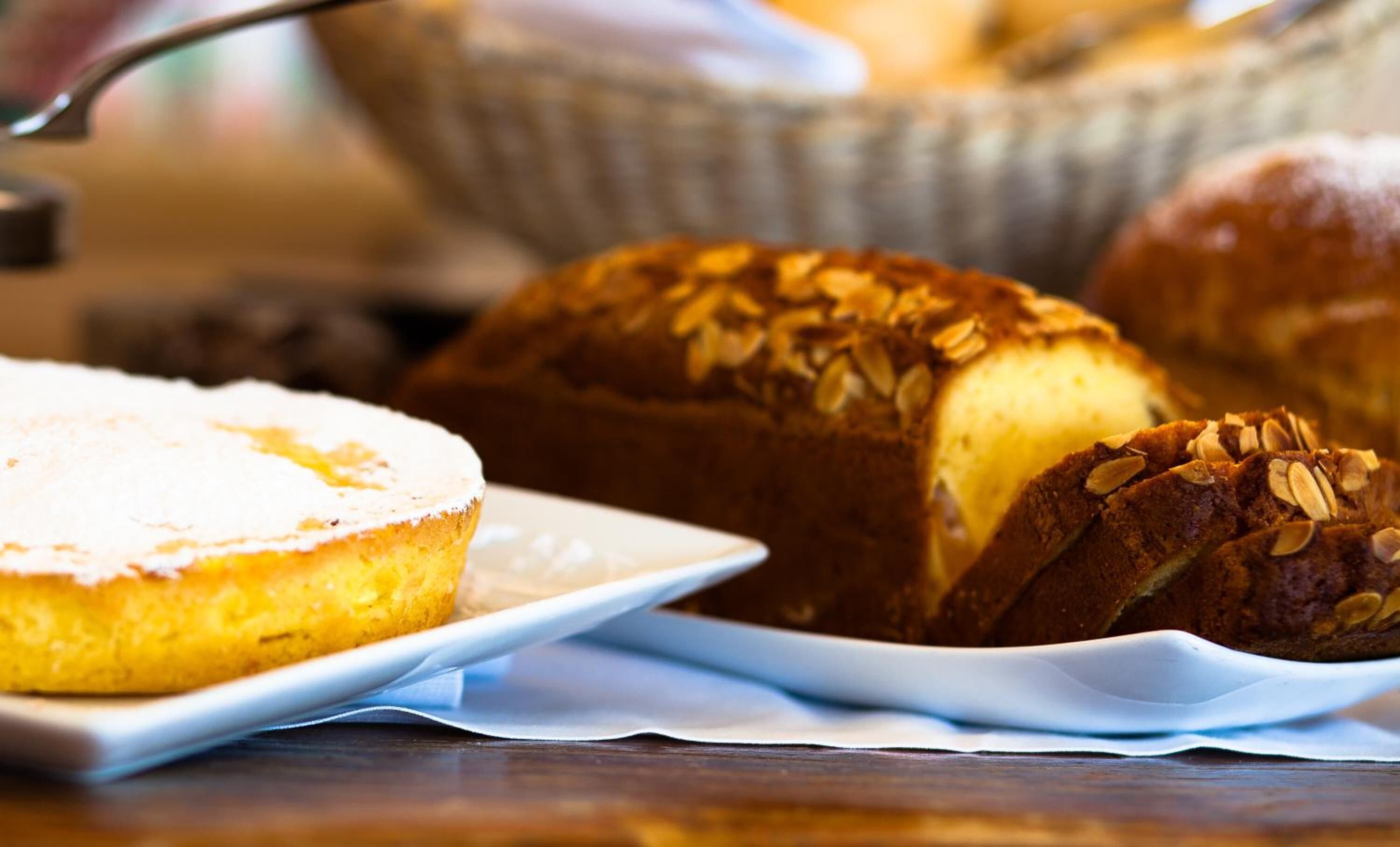 A loaf of bread with sliced almonds on a white plate.