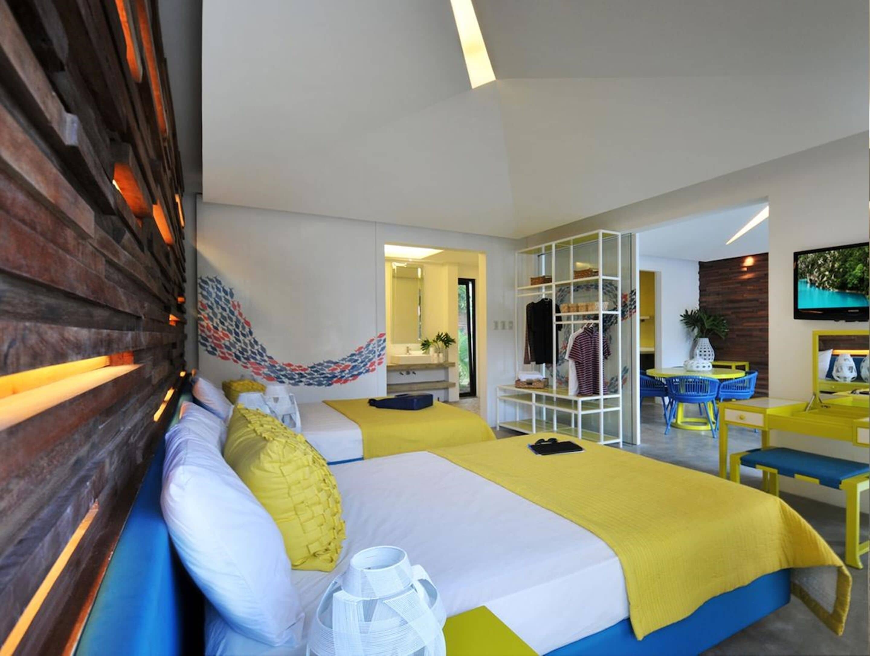 Une chambre d’hôtel comprenant un lit, un coin salon avec une table et des chaises, une armoire et un téléviseur.