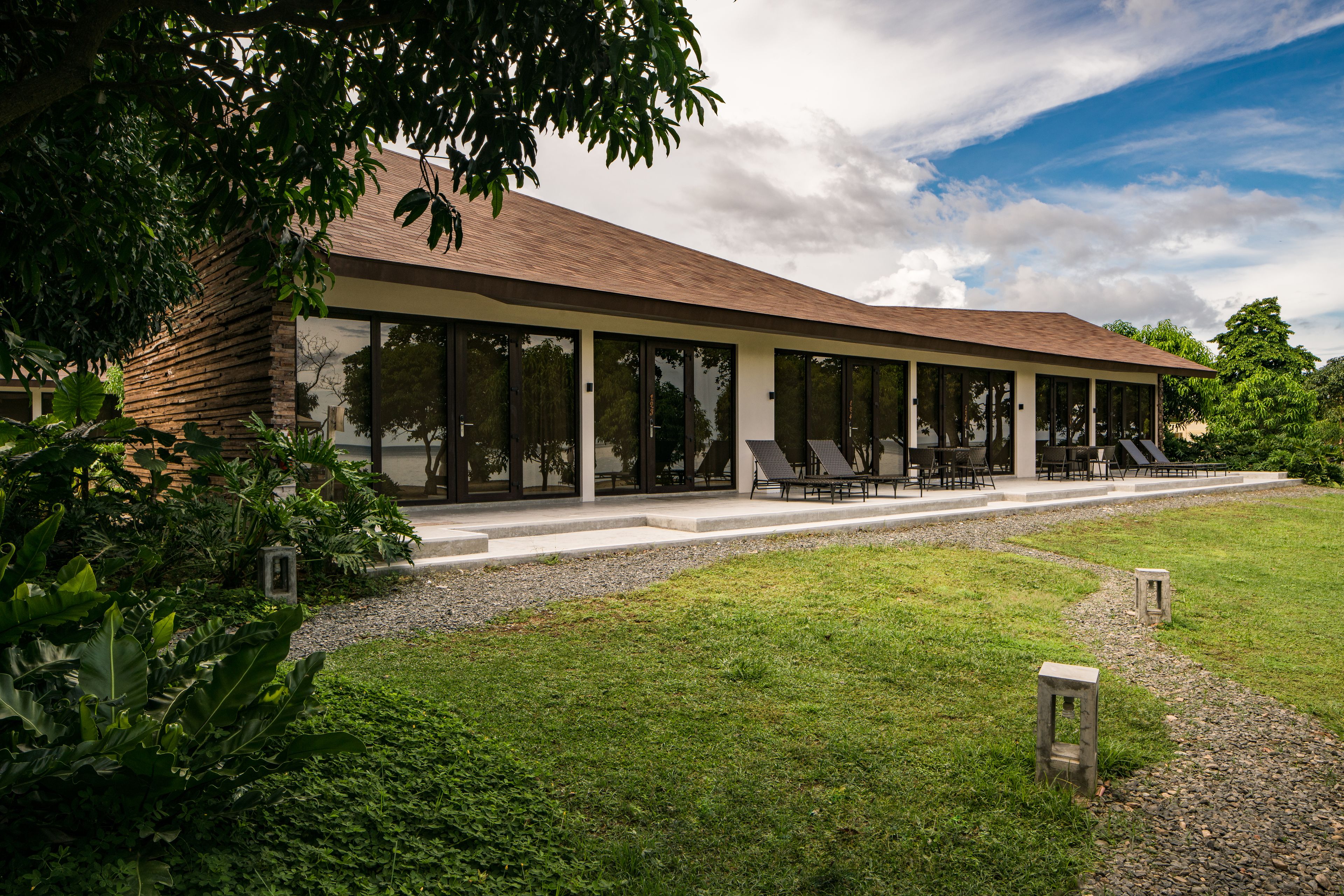 A modern building with large windows and a covered outdoor seating area.