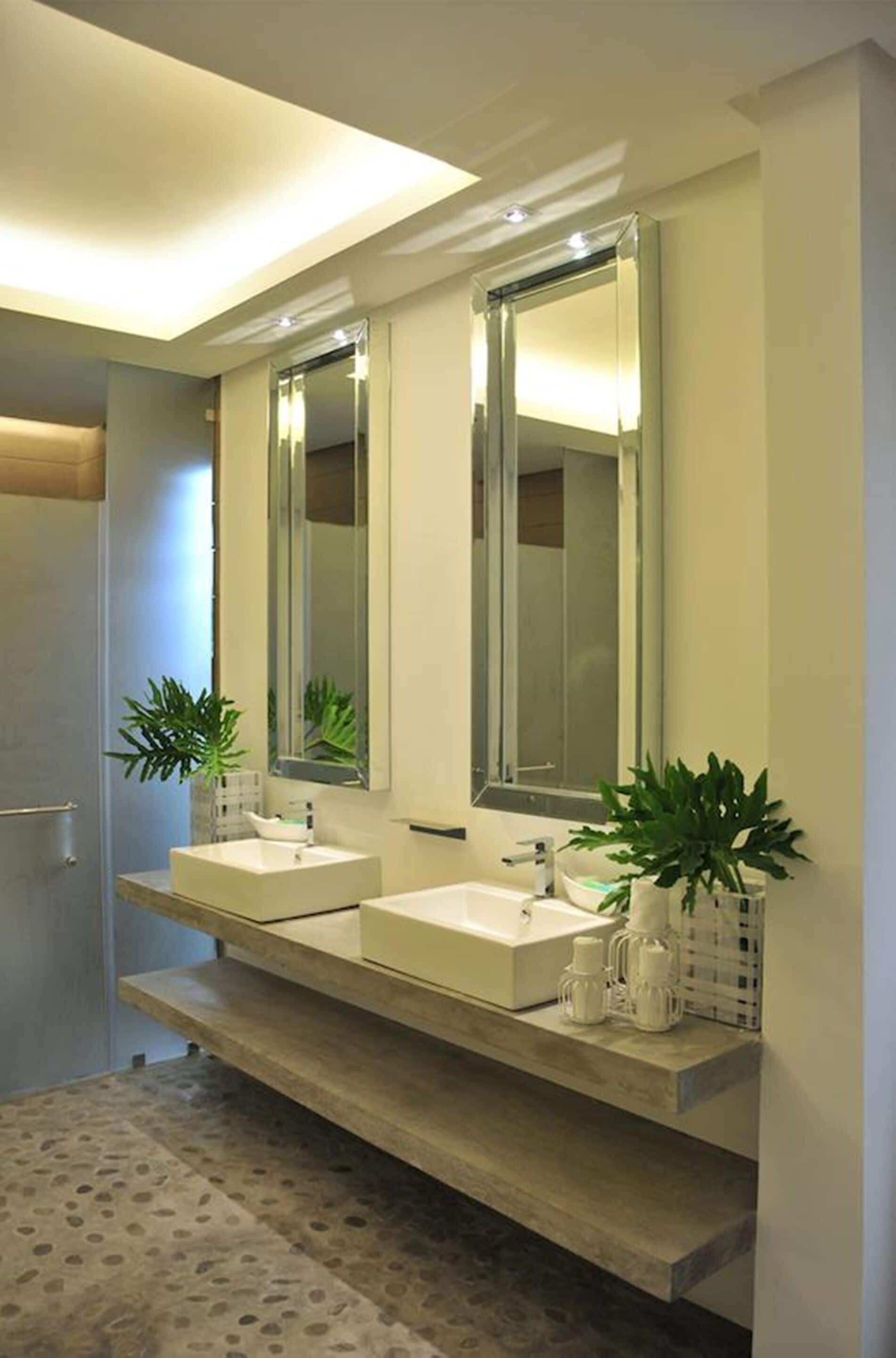 A modern bathroom with two sinks, large mirrors, and potted plants.
