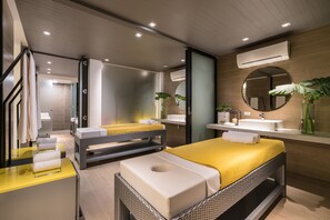 A modern hotel room with a large bed, a separate seating area, a bathroom with a large mirror, and a small plant.