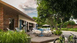 A modern outdoor patio with a dining table and chairs, a bicycle, and lush greenery. - Astoria Palawan (Puerto Princesa)