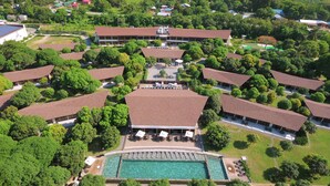 An aerial view of a resort with multiple bungalow-style buildings, a central swimming pool, and lush greenery surrounding the property. - Astoria Palawan (Puerto Princesa)