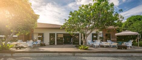 A modern building with a patio area featuring outdoor seating and a tree.