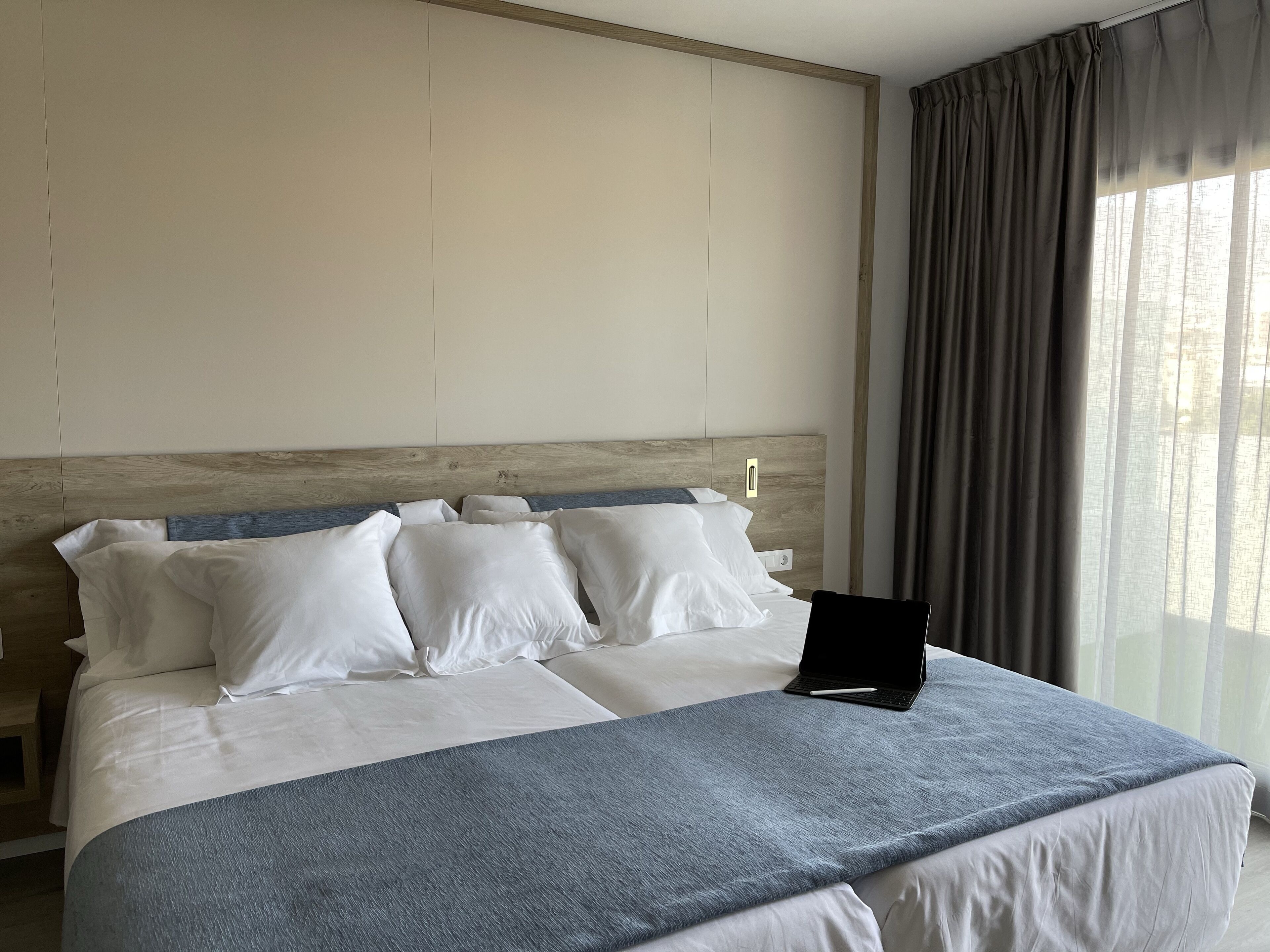 Una habitación de hotel con una cama grande, un cabecero de madera y una ventana con cortinas.
