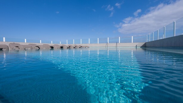 A clear blue swimming pool with a modern design, surrounded by a concrete deck and a metal railing. - Hotel AF Valle Orotava (Puerto de la Cruz)