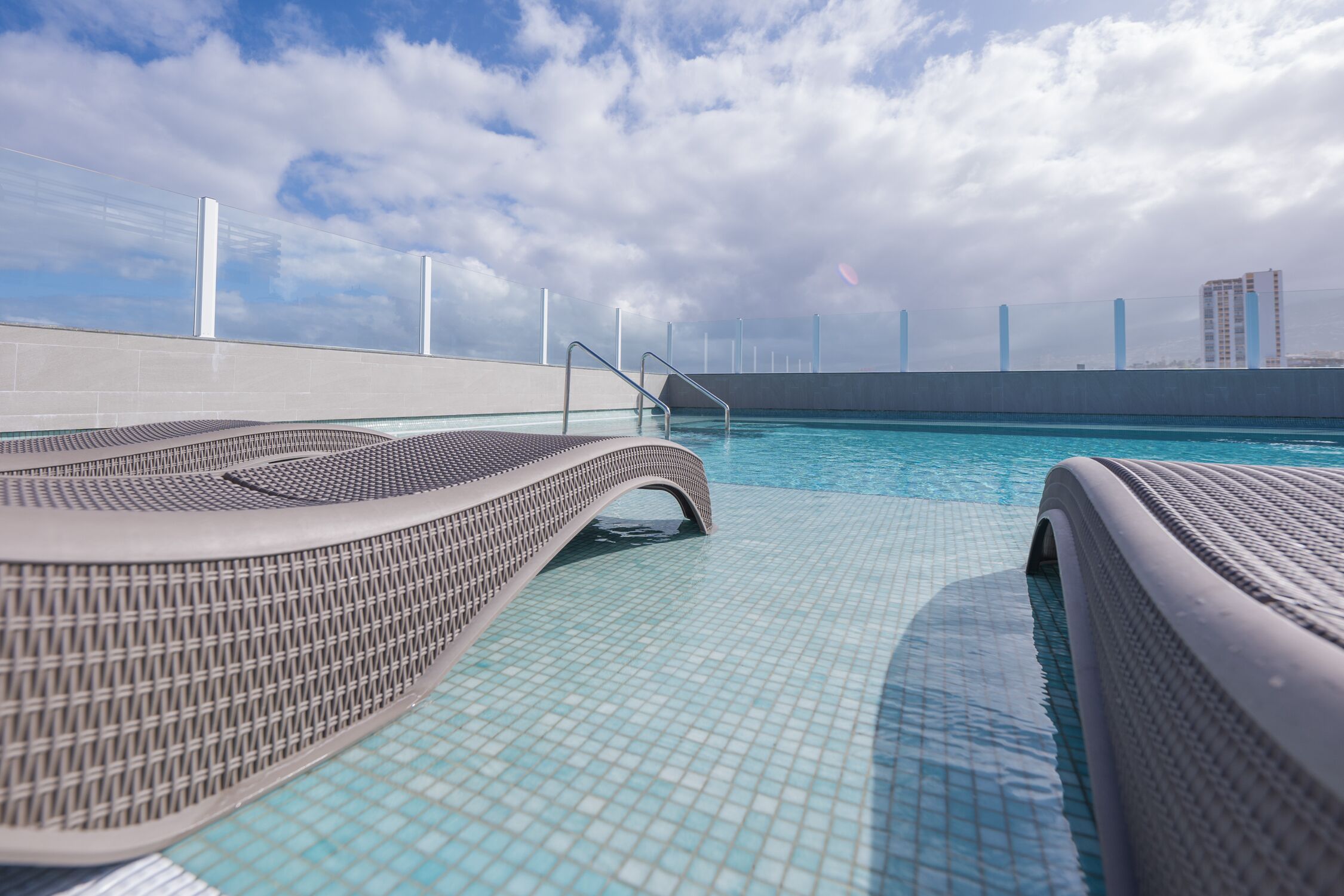 A modern infinity pool with a clear view of the city skyline in the background.