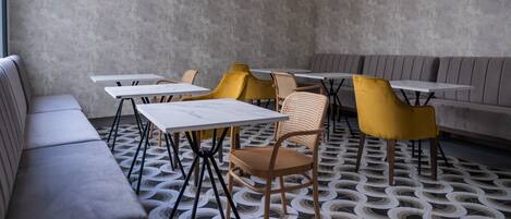 Interior de un restaurante moderno con suelo estampado, asientos grises y sillas amarillas.