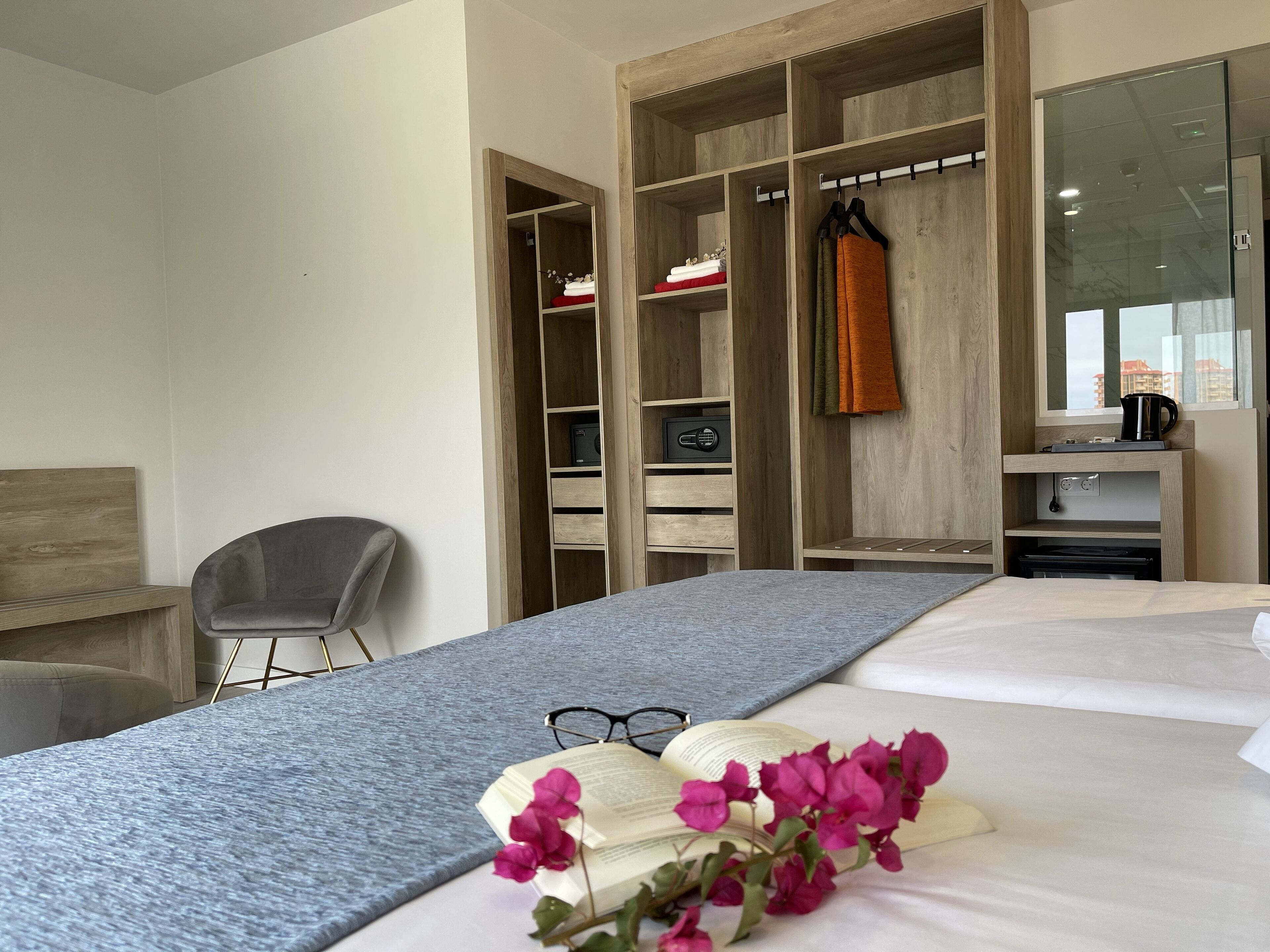 Ein Hotelzimmer mit Bett, Schreibtisch, Stuhl, Kleiderschrank und einer Kaffeemaschine.