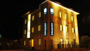 Et moderne hotel med en flad facade, mange vinduer og oplyst skiltning.