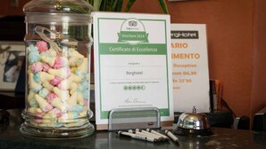 Et glas fyldt med farverige slik, et TripAdvisor-excellence certifikat og et skilt til receptionen.