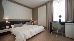 Et moderne hotelværelse med en stor seng, et skrivebord og en stol.