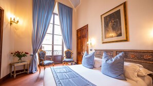 A hotel room with a large bed, two chairs, a nightstand, and a window with curtains. - B&B Galileo 2000 (Florence)