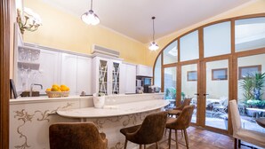 A kitchen with a curved island, bar stools, and a view through large glass doors. - B&B Galileo 2000 (Florence)