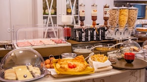 A buffet with various food items, including meats, cheeses, and a covered display of eggs. - B&B Galileo 2000 (Florence)