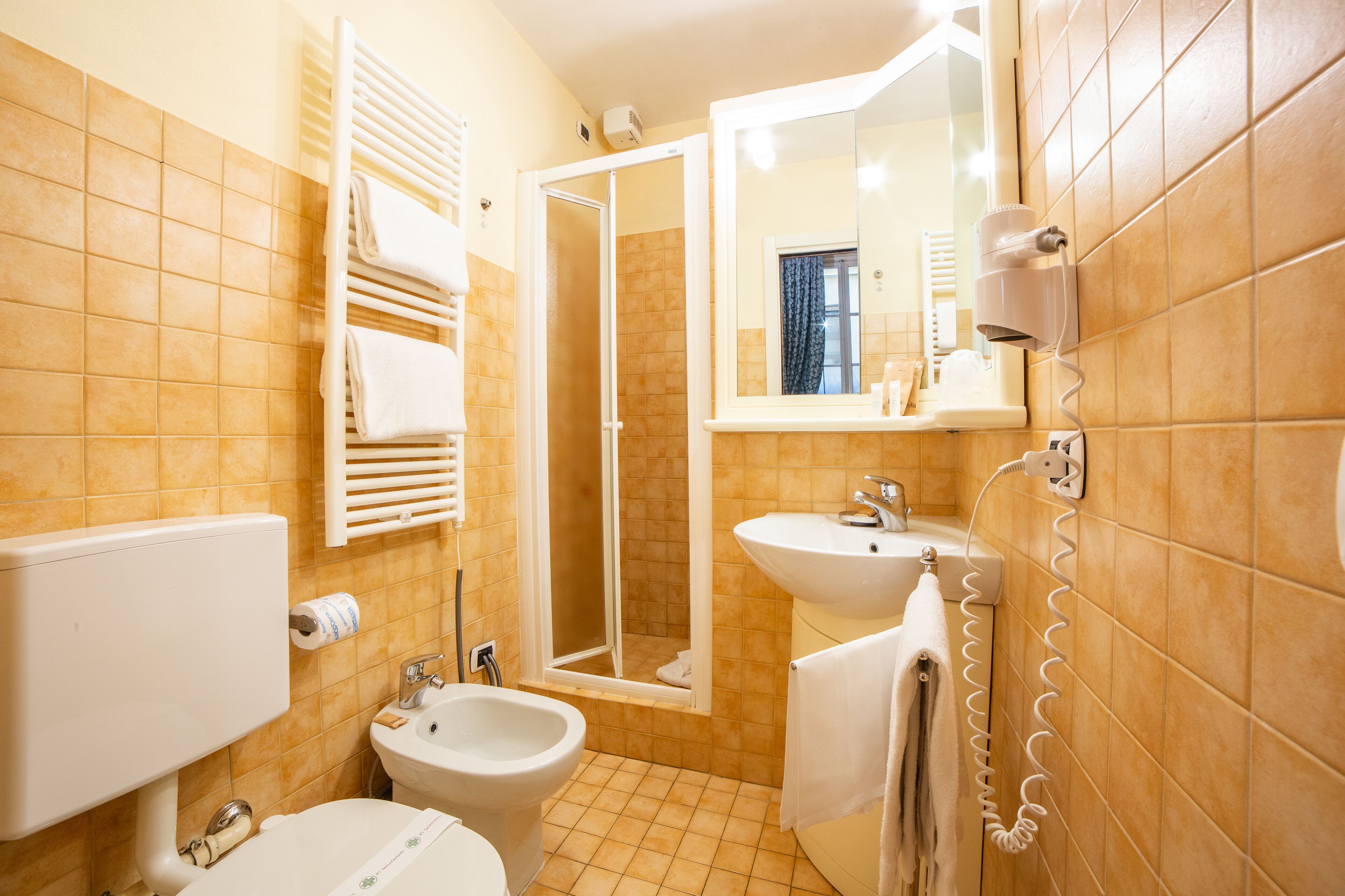 A bathroom with a toilet, bidet, sink, and a shower with a glass door.
