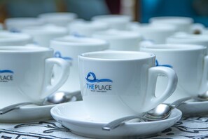 Una hilera de tazas blancas con asas y platillos, cada uno con un logotipo y texto.