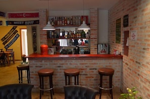 Uma área de bar com parede de tijolos, três banquetas e luminárias pendentes.