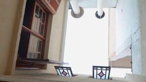 A view from a balcony with a window overlooking a building. There are two small, decorative glass panels on the balcony. - Escambo Hostel (Sao Paulo)